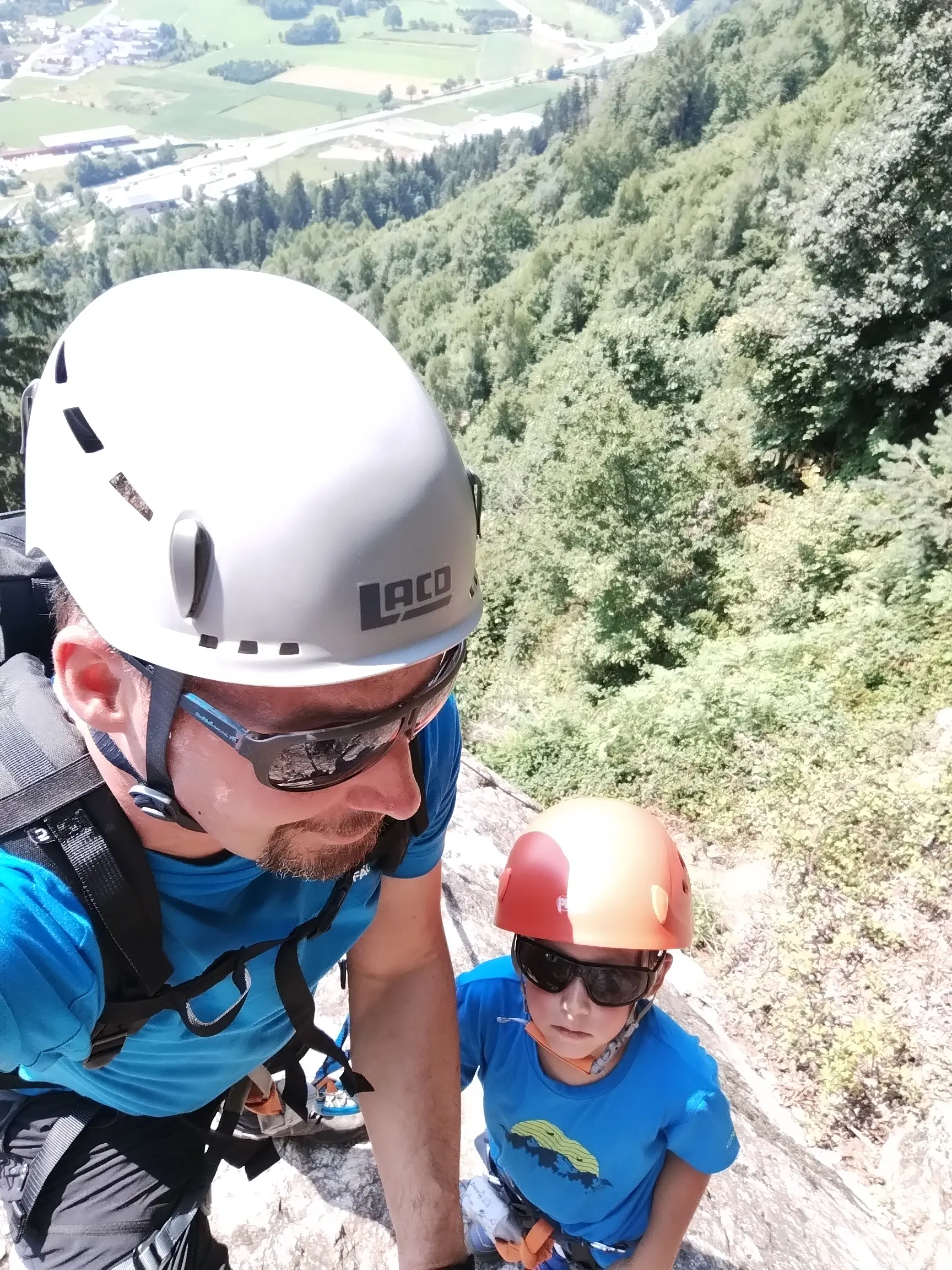 Marco Müller mit Kletterhelm und Sonnenbrille vor bewaldeter Kulisse